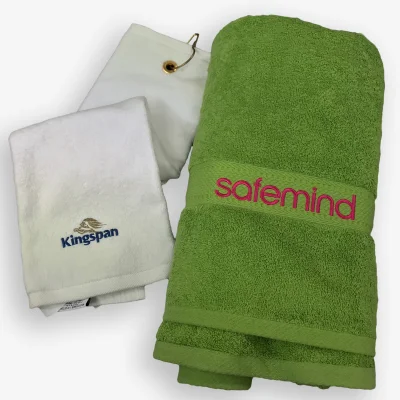 En frottéhandduk med broderad logotyp och en golfhandduk.